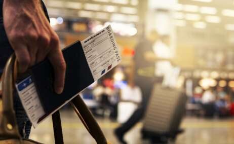 Una persona con pasaporte en mano y billetes de avión