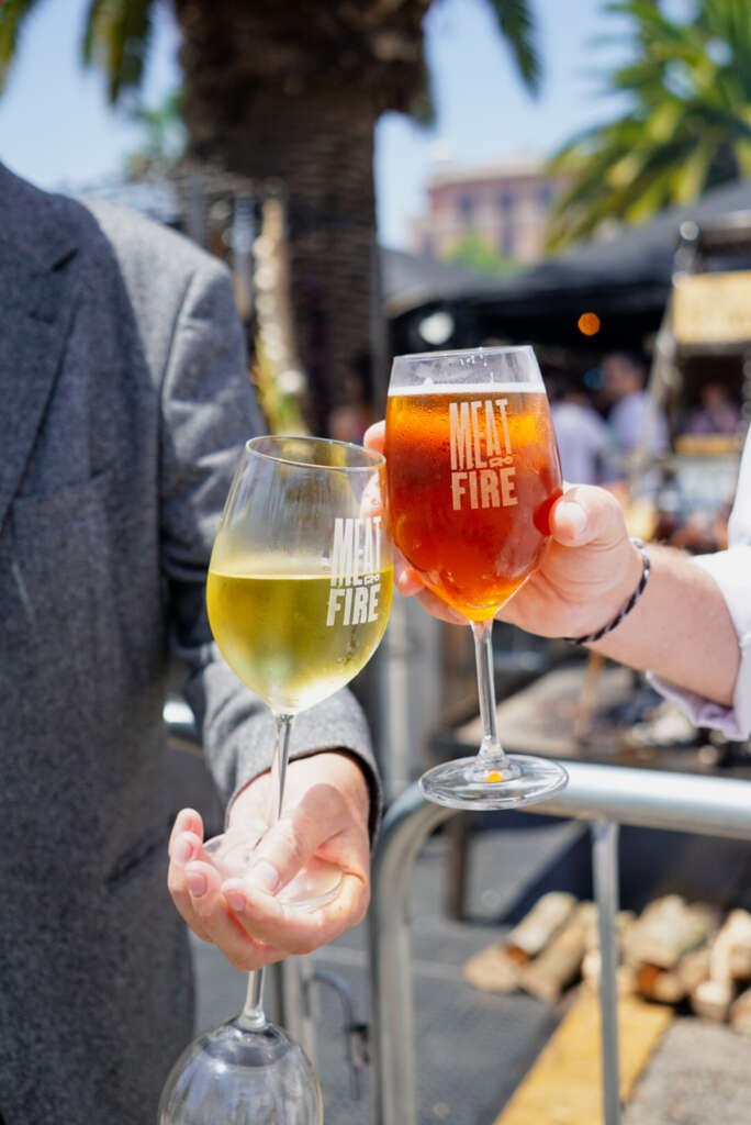 Dos personas chocan sus copas en el Meat&Fire