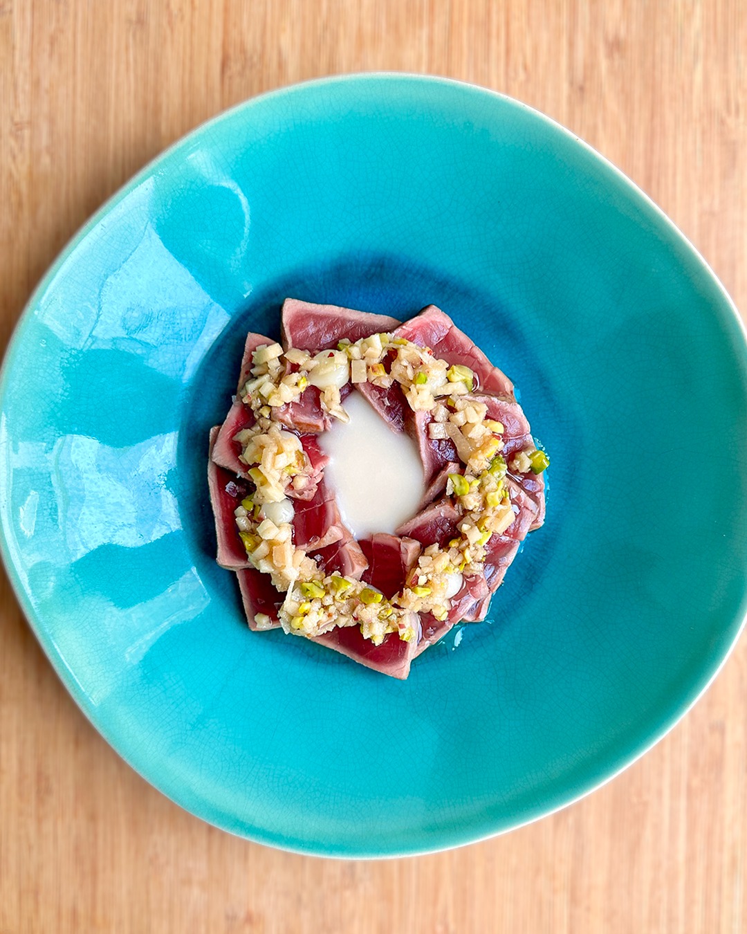 Un plato de Tataki de atún con crema de manzana ácida y puré de limón