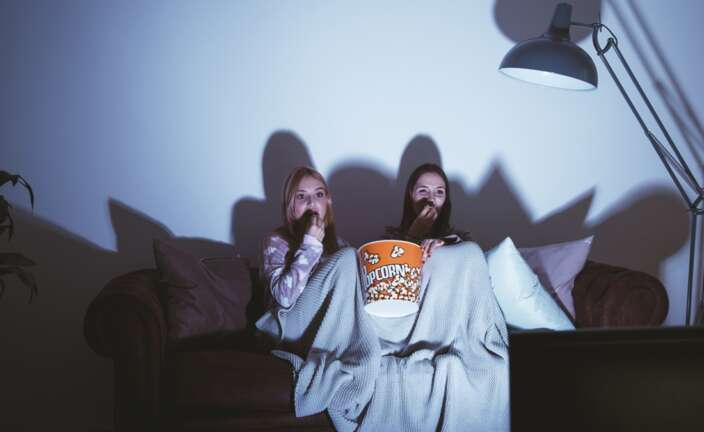 Unas chicas viendo una película de terror en el sofá