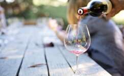 Una persona llena una copa de vino para una cata