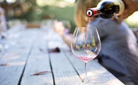 Una persona llena una copa de vino para una cata