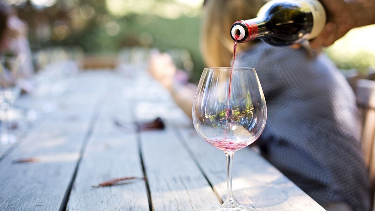 Una persona llena una copa de vino para una cata