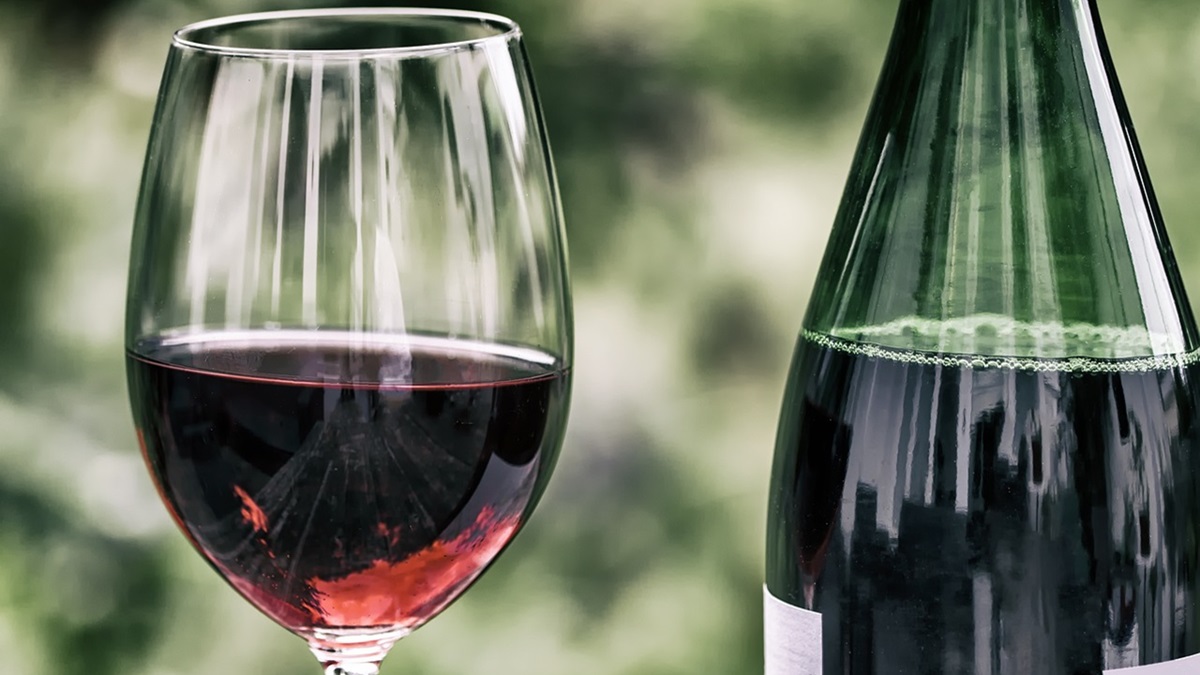 Una botella de vino tinto junto a una copa
