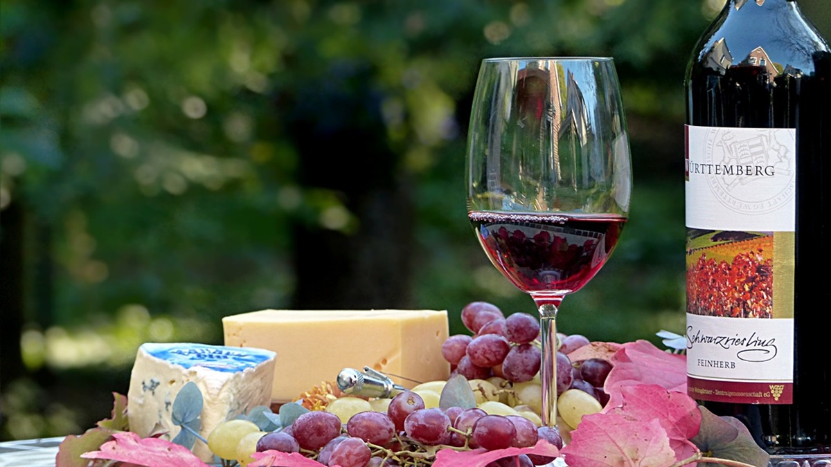 Una botella de vino tinto junto a una copa y algunos aperitivos