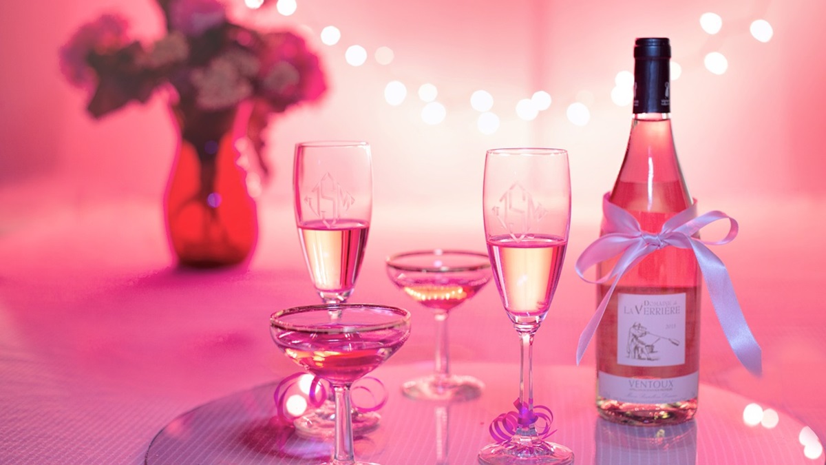 Una botella junto a unas copas de vino rosado
