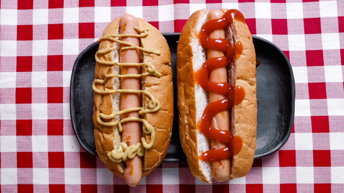 Dos perritos calientes con diferentes salsas