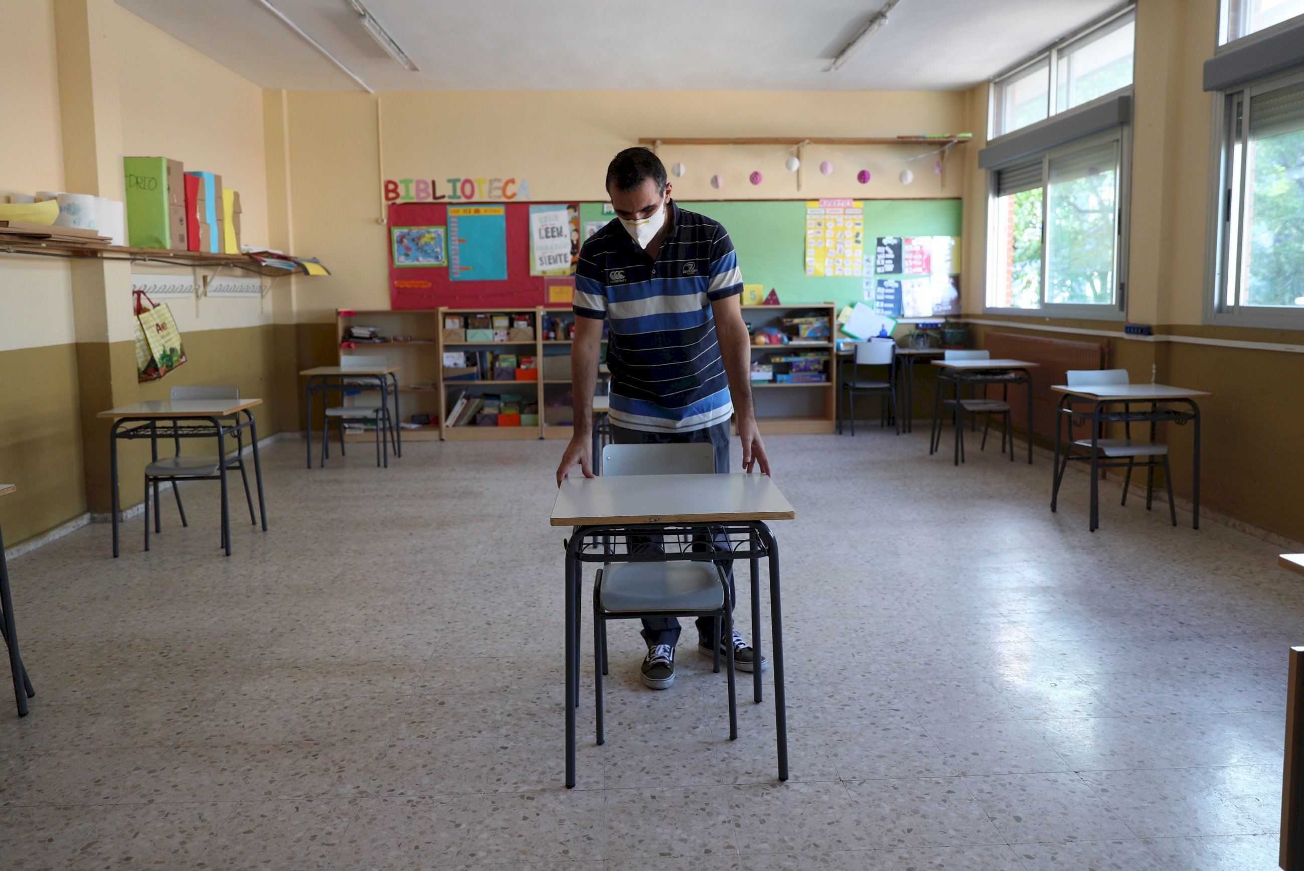 Un profesor coloca las mesas para mantener la distancia de seguridad en el colegio Jaime Vera en el primer día de vuelta voluntaria a las aulas para los niños de primaria de Torrejón de Ardoz, Madrid. EFE
