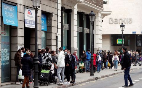 Un numeroso grupo de personas guarda cola durante el reparto de alimentos llevado a cabo este lunes por integrantes de la plataforma integrada por organizaciones sociales "Esperanza Obrera" en el edificio ocupado la semana pasada en el centro financiero de la ciudad. EFE/Kai Försterling