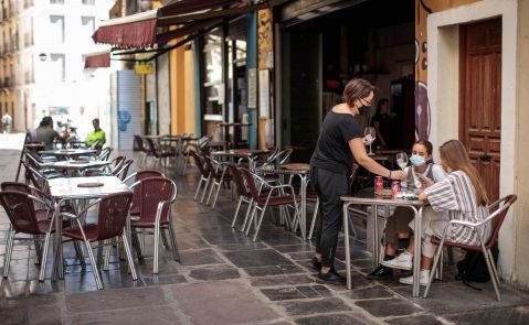 Una camarera atiende una mesa de una terraza en el centro de València. El sector servicios es el más afectado por los ERTE