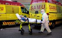 Un sanitarios con equipo de protección especial para evitar contagios de coronavirus, traslada a un paciente de una ambulancia a urgencias del Hospital Clínico de València / EFE