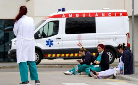 Varios sanitarios descansan en la puerta de un hospital./ EFE