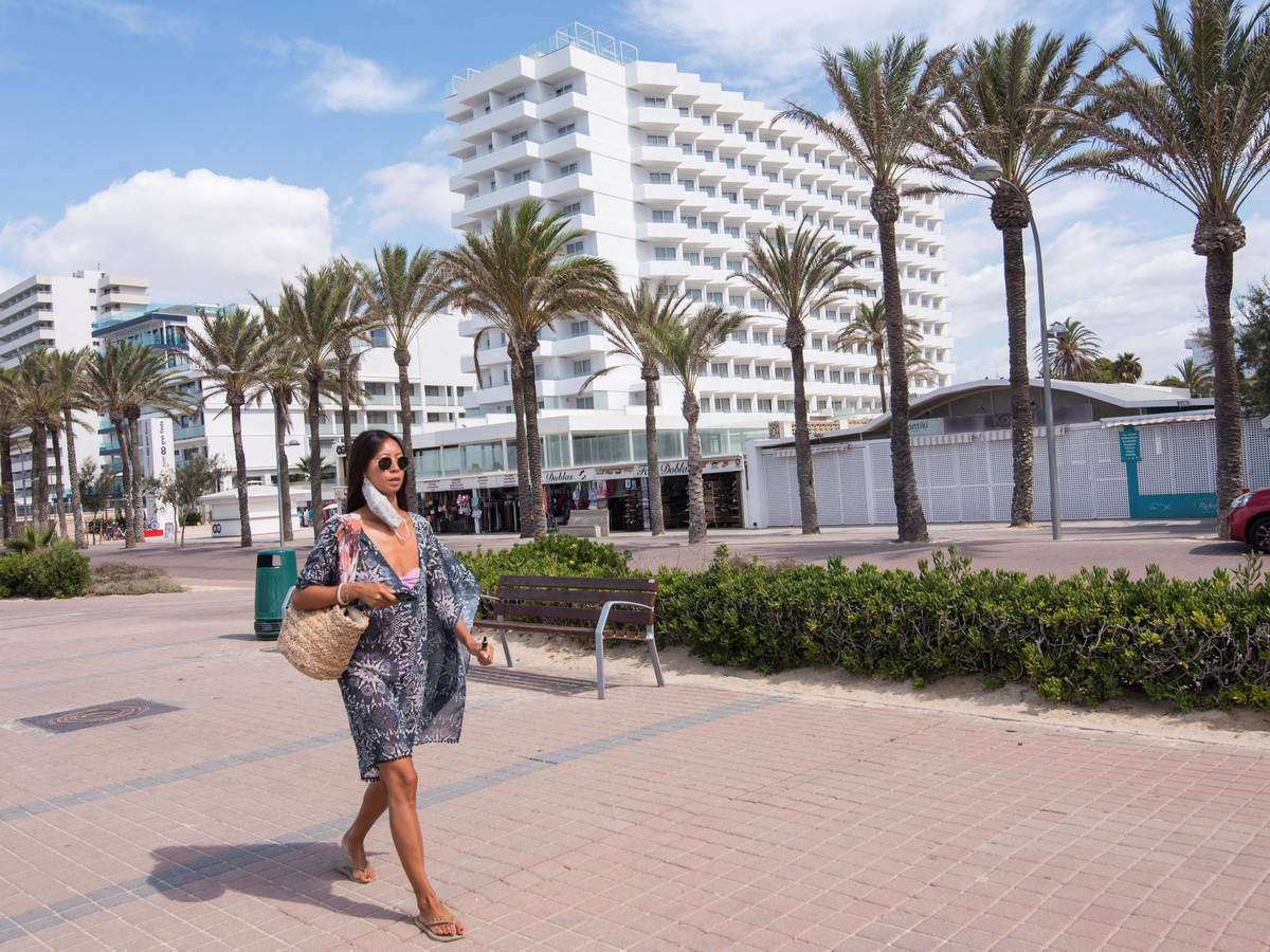 Señora paseando al lado de un complejo de hoteles en la playa.
