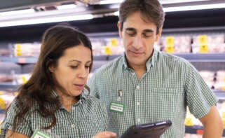 Dos trabajadores de Mercadona miran un dispositivo electrónico.
