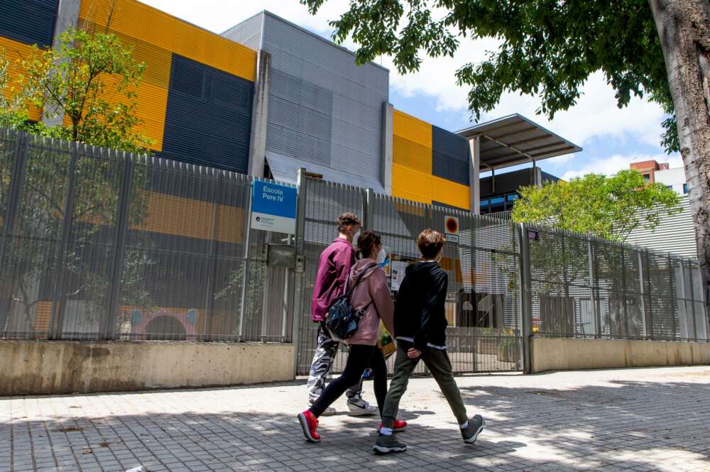 Varios adolescentes pasean frente a una escuela cerrada. Foto: Efe