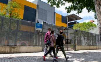 Varios adolescentes pasean frente a una escuela cerrada. Foto: Efe