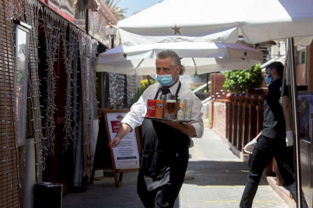 Un camarero lleva su pedido a unos clientes a una de las terrazas del Puerto Olímpico de Barcelona / EFE