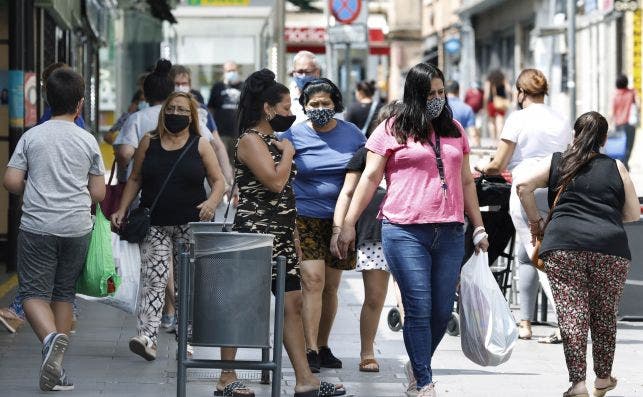 Ciudadanos con mascarillas para protegerse del coronavirus pasean por las calles de l'Hospitalet de Llobregat (Barcelona) / EFE