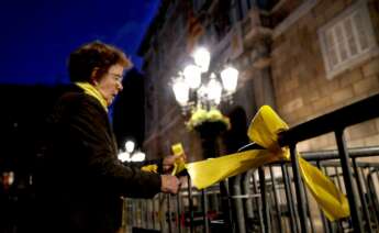 Una mujer coloca lazos amarillos en una valla. Foto: EFE.