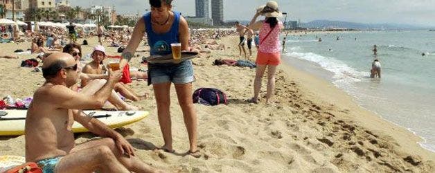 Una camarera sirve una cerveza en la playa. EFE