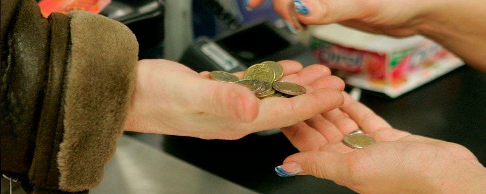 Una cajera cuenta las monedas de un cliente en un supermercado