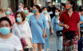 Varias personas pasean de compras por una calle llena de comercios tras la pandemia del coronavirus./ EFE