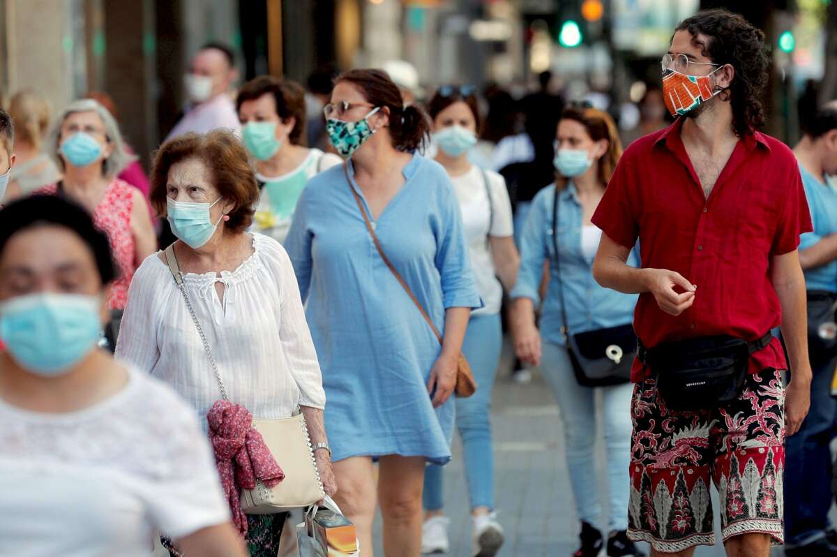 Varias personas pasean de compras por una calle llena de comercios tras la pandemia del coronavirus./ EFE