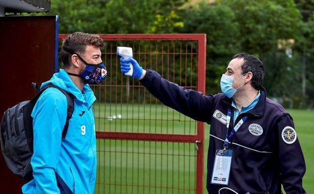 Un miembro de la seguridad del Eibar toma la temperatura al futbolista Sergi Enrich. EFE