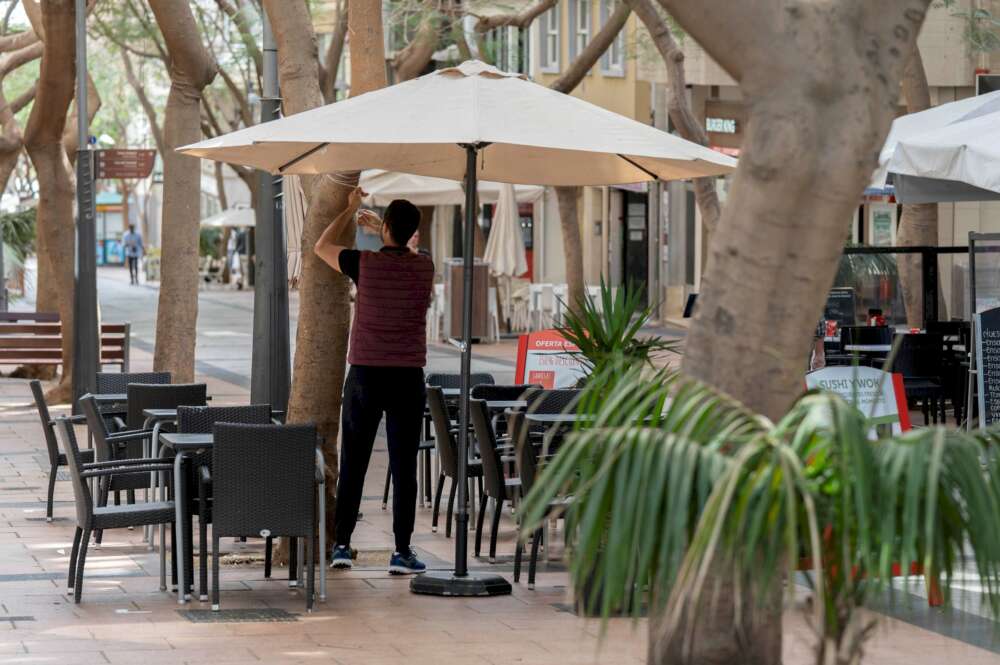 Un camarero coloca una sombrilla en la terraza. EFE/Miguel Barreto/Archivo