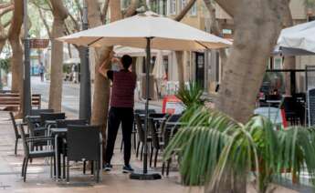 Un camarero coloca una sombrilla en la terraza. EFE/Miguel Barreto/Archivo