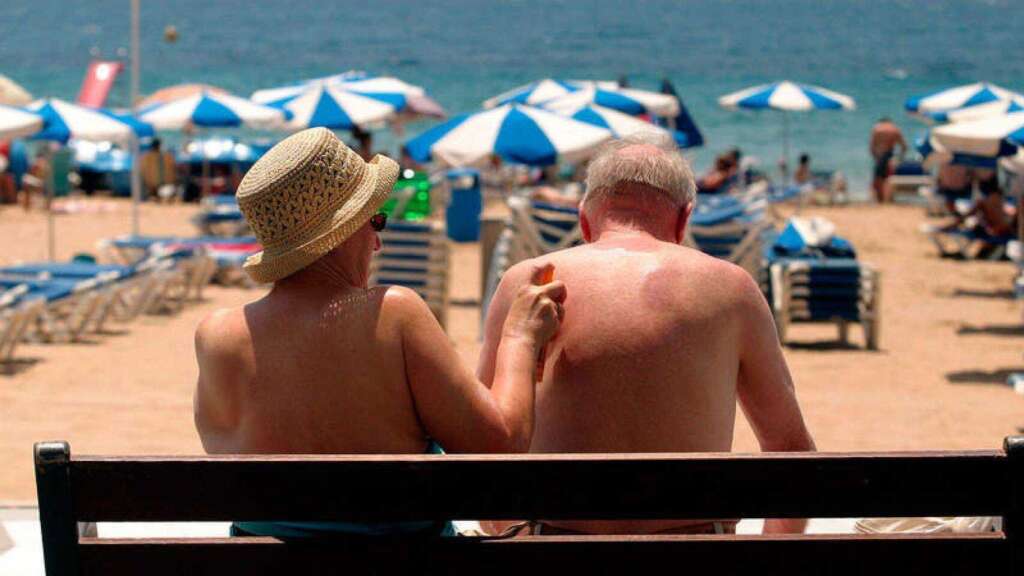 Dos personas mayores que viajan a través del Imserso se ponen crema en la playa / EFE