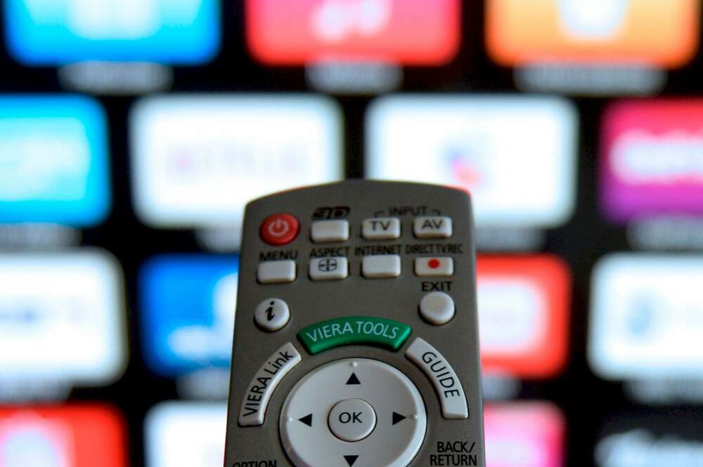 Un mando de televisión frente a una pantalla donde se muestran varias plataformas