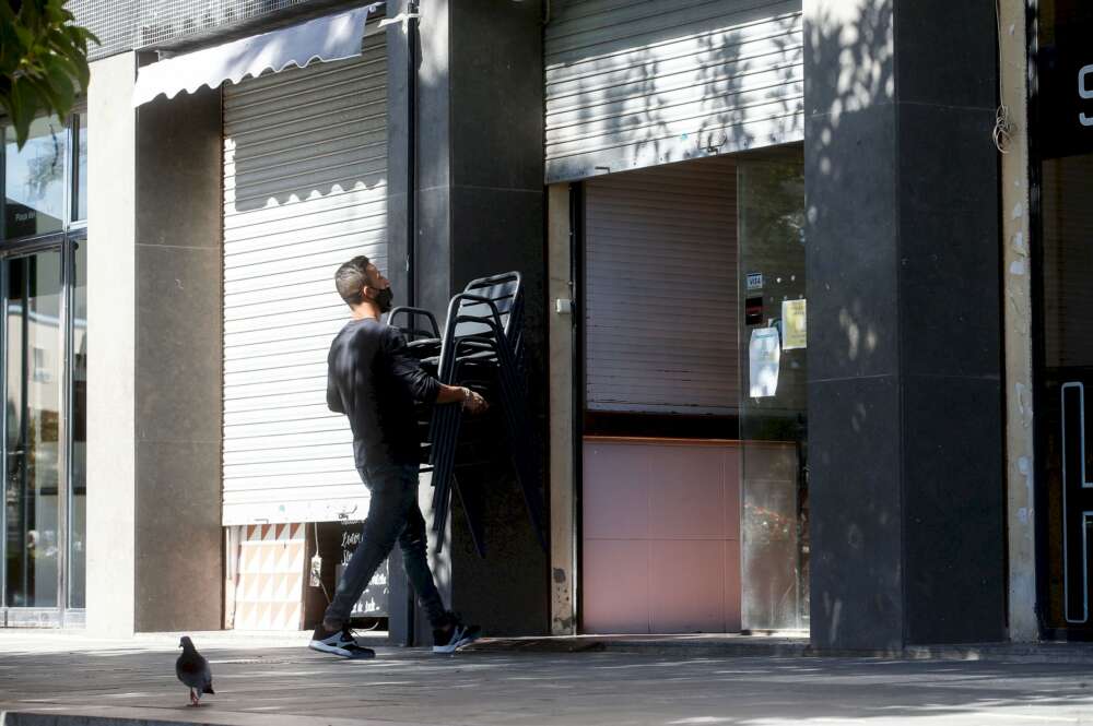 Un camarero recoge las sillas de una terraza de un restaurante del barrio de la Barceloneta de Barcelona. EFE/Quique García