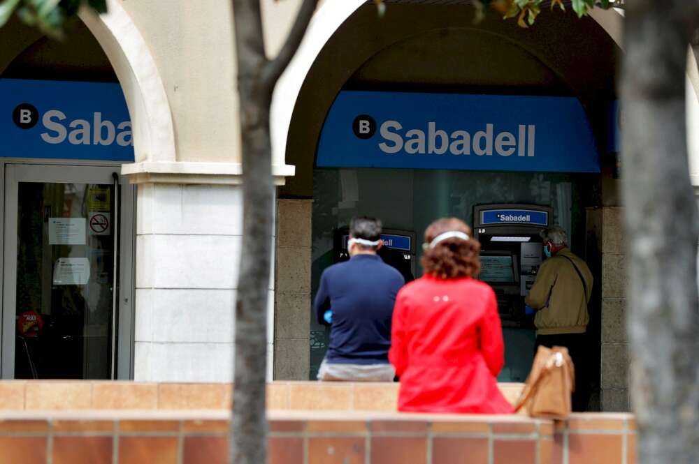 Varias personas esperan ante una sucursal de un banco que mantienen sus puertas abiertas durante la crisis sanitaria del coronavirus. EFE/Manuel Bruque