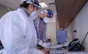 Una pareja de profesionales sanitarios manipula unos documentos durante la pandemia de Covid-19. Foto: EFE