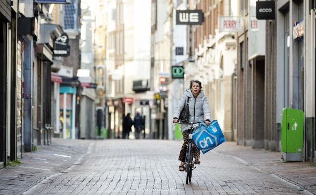 Una mujer en bicicleta por una calle comercial de Ámsteradm (Países Bajos), con la mayoría de comercios cerrados por el coronavirus / EFE