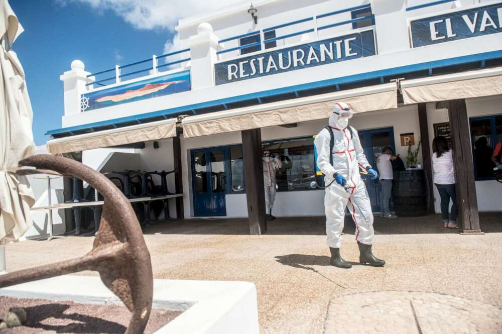 Imagen de archivo de personal desinfectando la puerta de un restaurante en La Graciosa (Canarias) durante la desescalada / EFE