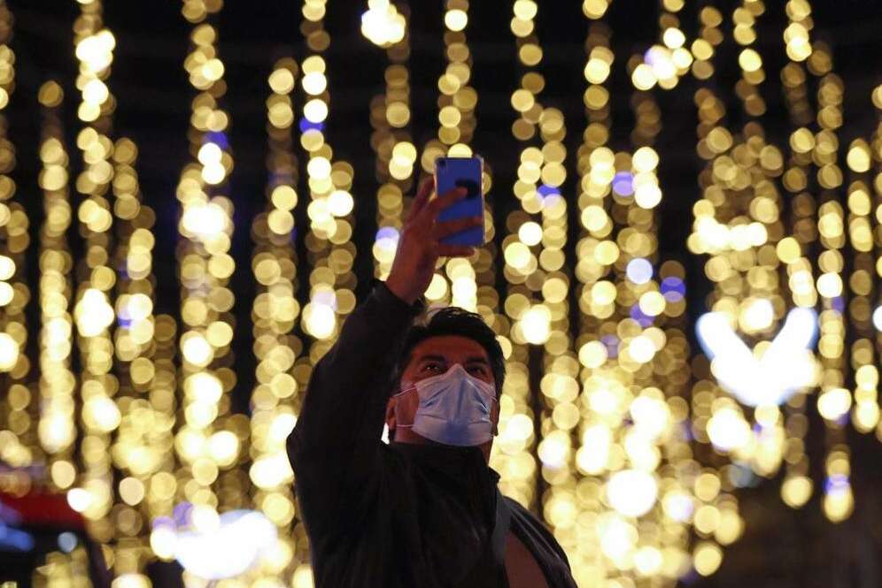 Un transeúnte se fotografía con las luces de Navidad del centro de Barcelona. (EFE)