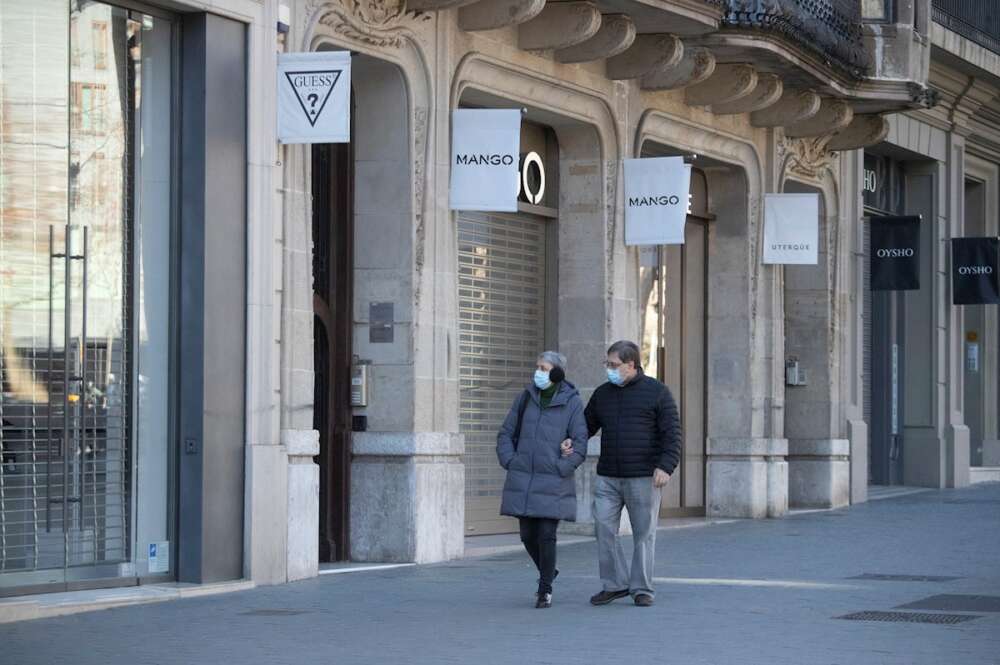 Una pareja pasa por delante de varias tiendas de ropa cerradas este sábado en Barcelona. La tercera ola de la epidemia de COVID sigue aumentando en Cataluña, donde en la última semana se han diagnosticado 24.716 nuevos contagios, 4.527 de ellos ayer, y 408 fallecidos, de los que 64 han sido notificados en las últimas 24 horas. EFE/Marta Pérez