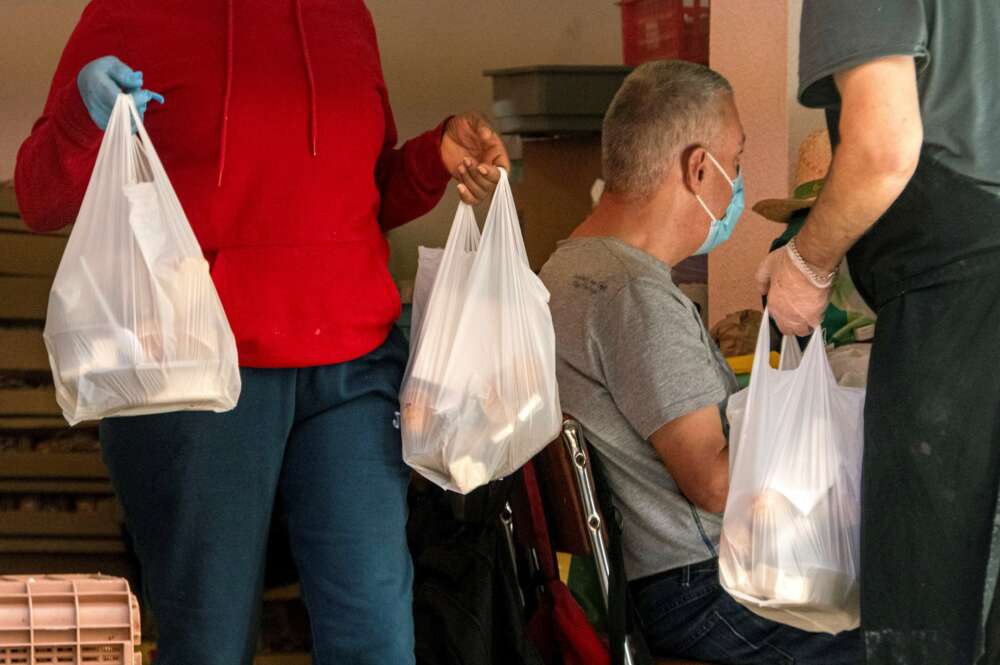 Un grupo de voluntarios participa en un reparto de alimentos a personas en situación de pobreza durante la pandemia de coronavirus. EFE/Cati Cladera