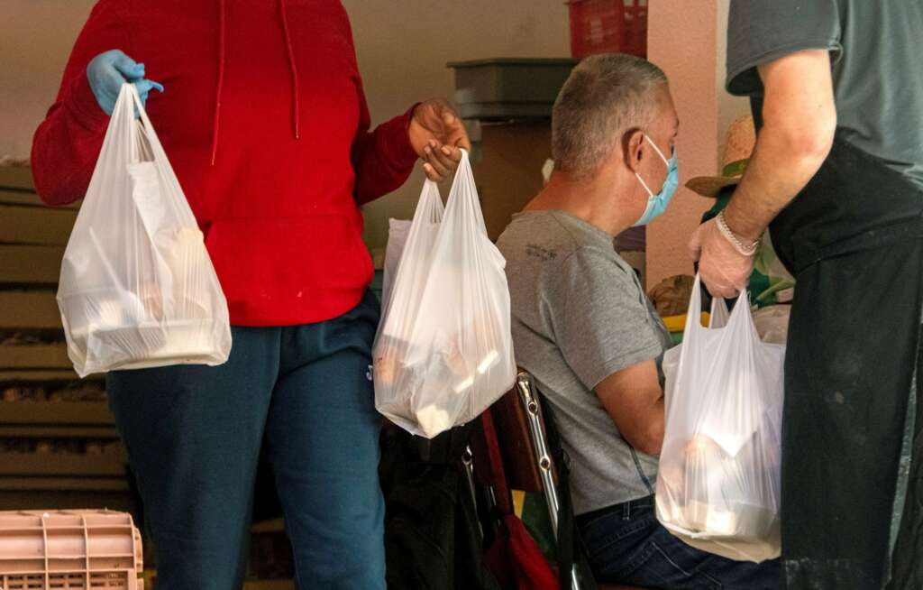 Un grupo de voluntarios participa en un reparto de alimentos a personas en situación de pobreza durante la pandemia de coronavirus. EFE/Cati Cladera