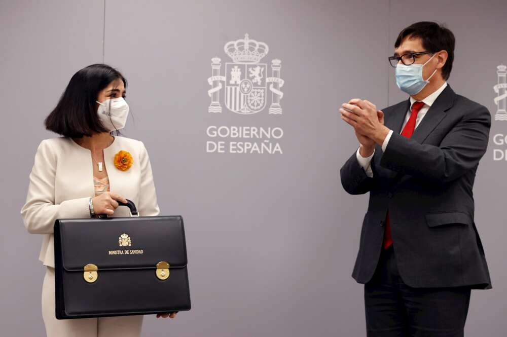 La nueva ministra de Sanidad, Carolina Darias, recibe los aplausos de su predecesor Salvador Illa mientras posa con su nuevo maletín tras la ceremonia de traspaso de la cartera celebrada en el Ministerio de Sanidad, el 27 de enero de 2021 | EFE/CM/Archivo