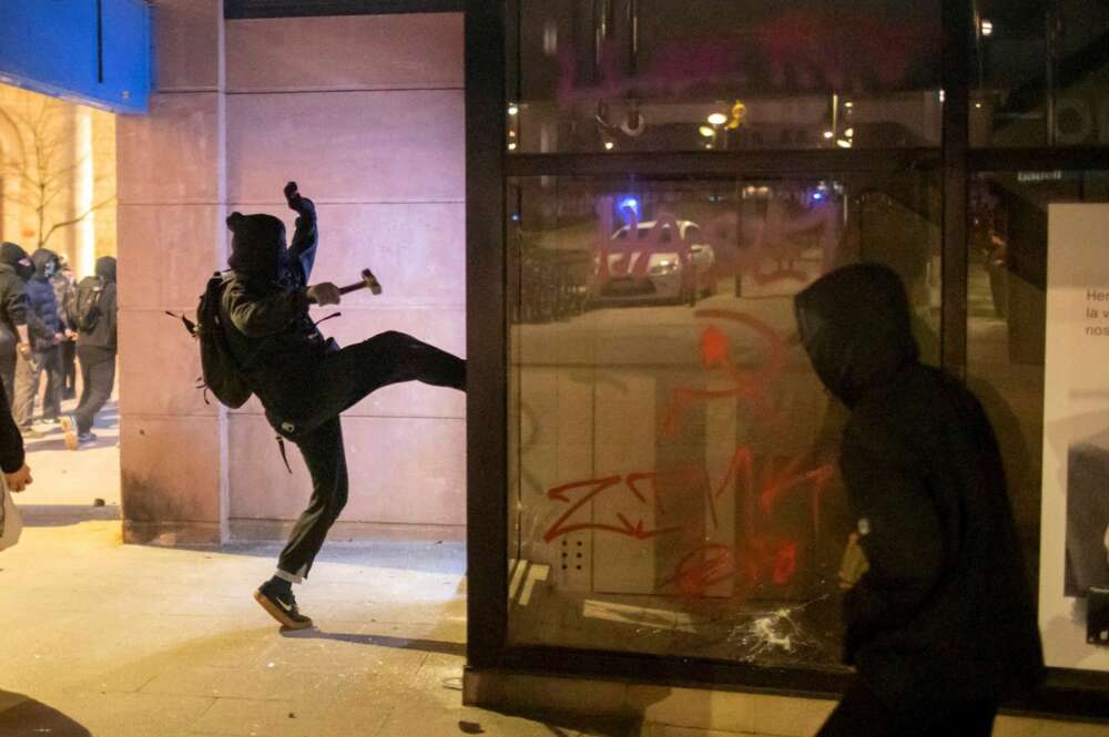 Un joven ataca un comercio durante los disturbios posteriores a la manifestación celebrada este viernes en Girona en protesta por la detención del rapero Pablo Hasél, acusado de delitos de enaltecimiento del terrorismo e injurias a la Corona. EFE/Toni Vilches