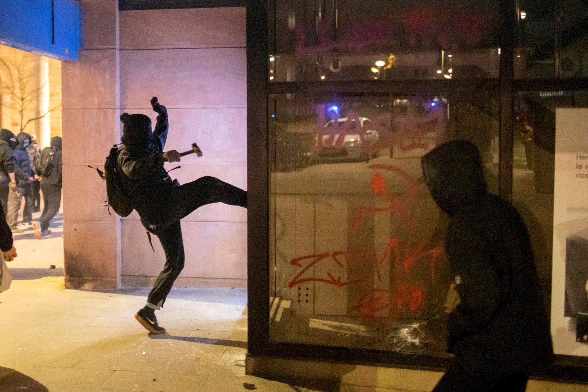Un joven ataca un comercio durante los disturbios posteriores a la manifestación celebrada este viernes en Girona en protesta por la detención del rapero Pablo Hasél, acusado de delitos de enaltecimiento del terrorismo e injurias a la Corona. EFE/Toni Vilches