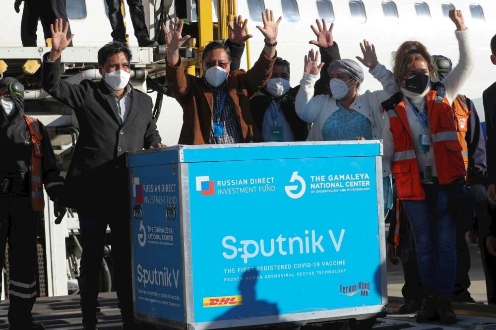 El presidente de Boliva, Luis Arce, (2i) saluda junto a un contenedor con dosis de la vacuna rusa Sputnik V el 28 de enero de 2021, en el Aeropuerto Internacional de El Alto (Bolivia). EFE/Martin Alipaz