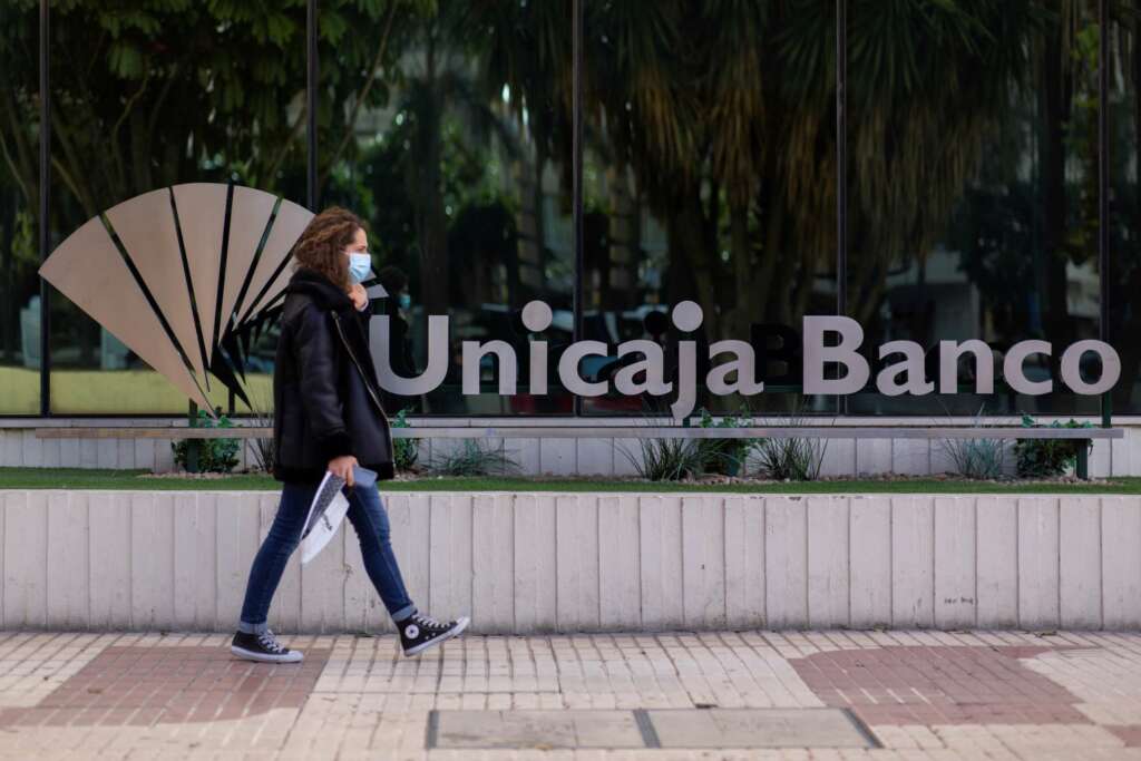 Una mujer pasa ante la sede de Unicaja en Málaga, antes de que se formalice su fusión definitiva con Liberbank que reducirá la competencia en el medio rural. EFE/Carlos Díaz