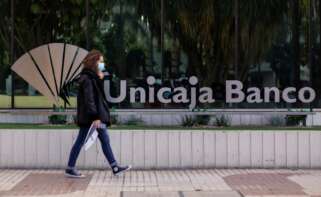 Una mujer pasa ante la sede de Unicaja en Málaga, antes de que se formalice su fusión definitiva con Liberbank que reducirá la competencia en el medio rural. EFE/Carlos Díaz