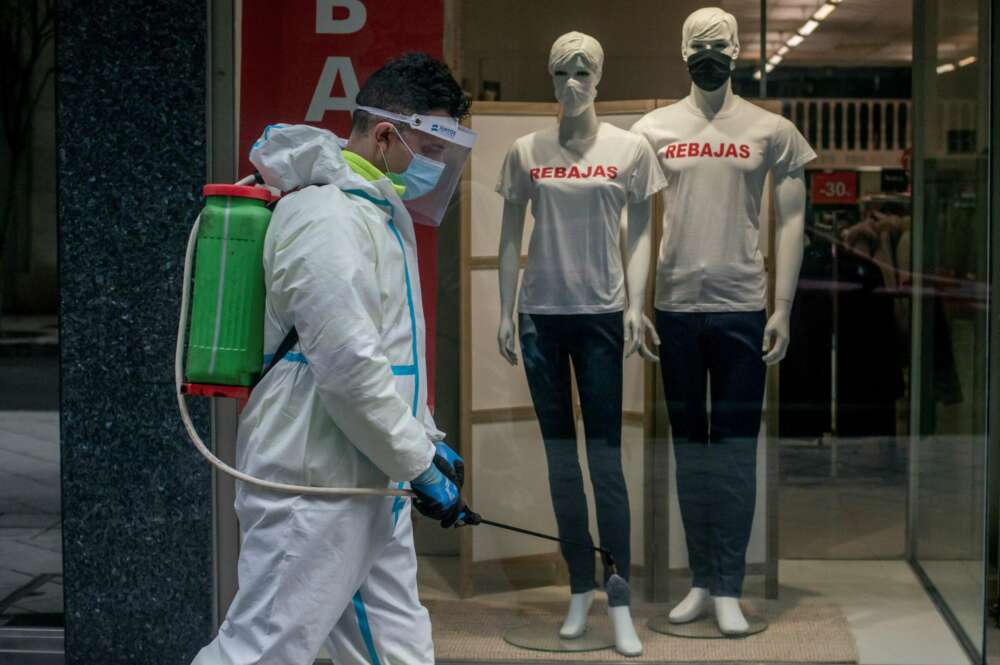 Un empleado municipal desinfecta una calle de Ourense durante la campaña de rebajas de enero, que ha hundido al sector textil. EFE/Brais Lorenzo