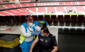 Un policía recibe la primera dosis durante el primer día de vacunación contra la covid-19 en el Wanda Metropolitano. EFE/Juan Carlos Hidalgo