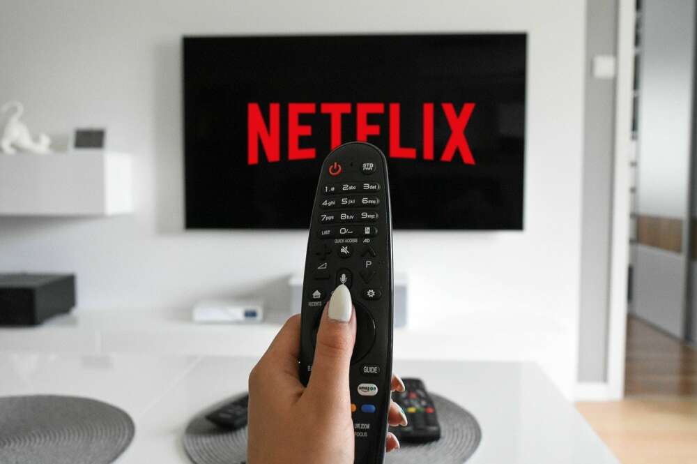 Imagen de un mando frente a un televisor que inicia Netflix